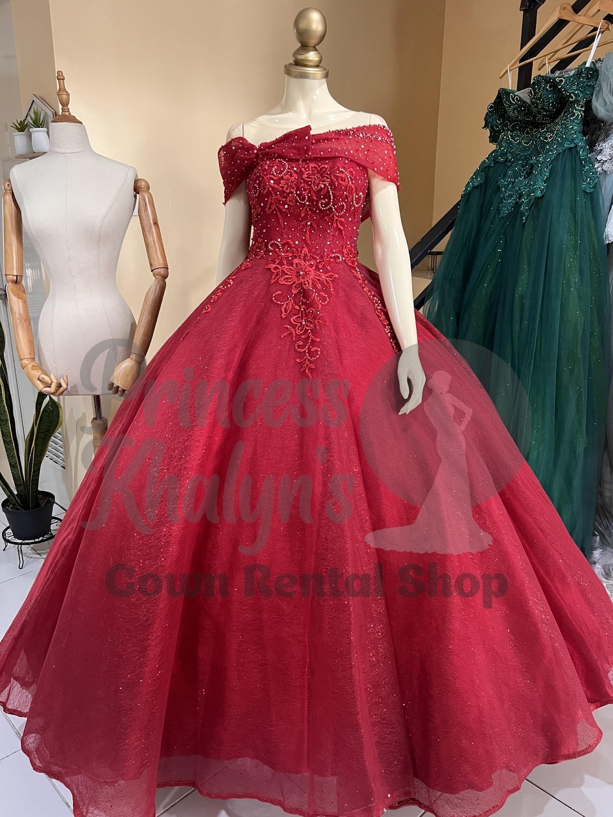 Red off-shoulder gown with floral embroidery, beaded accents, and a decorative bow on the neckline