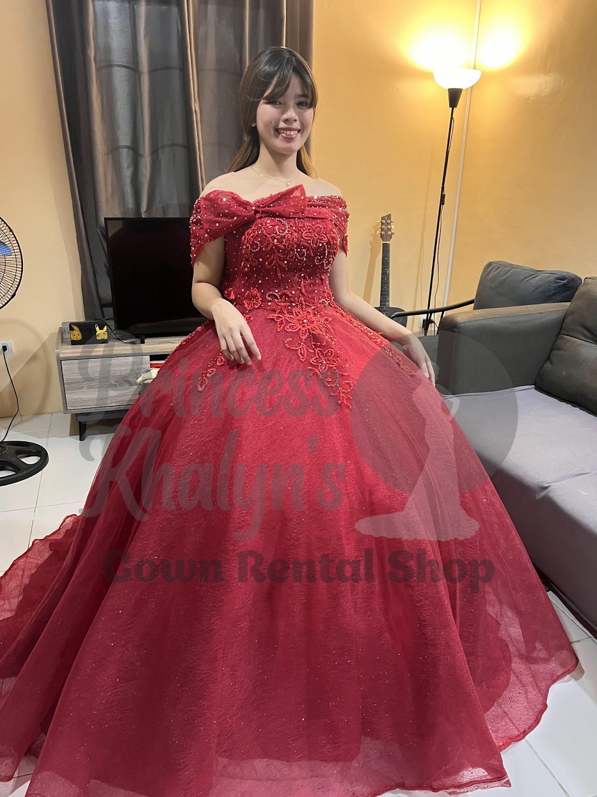 Red off-shoulder gown with floral embroidery, bead embellishments, and a statement bow on the neckline