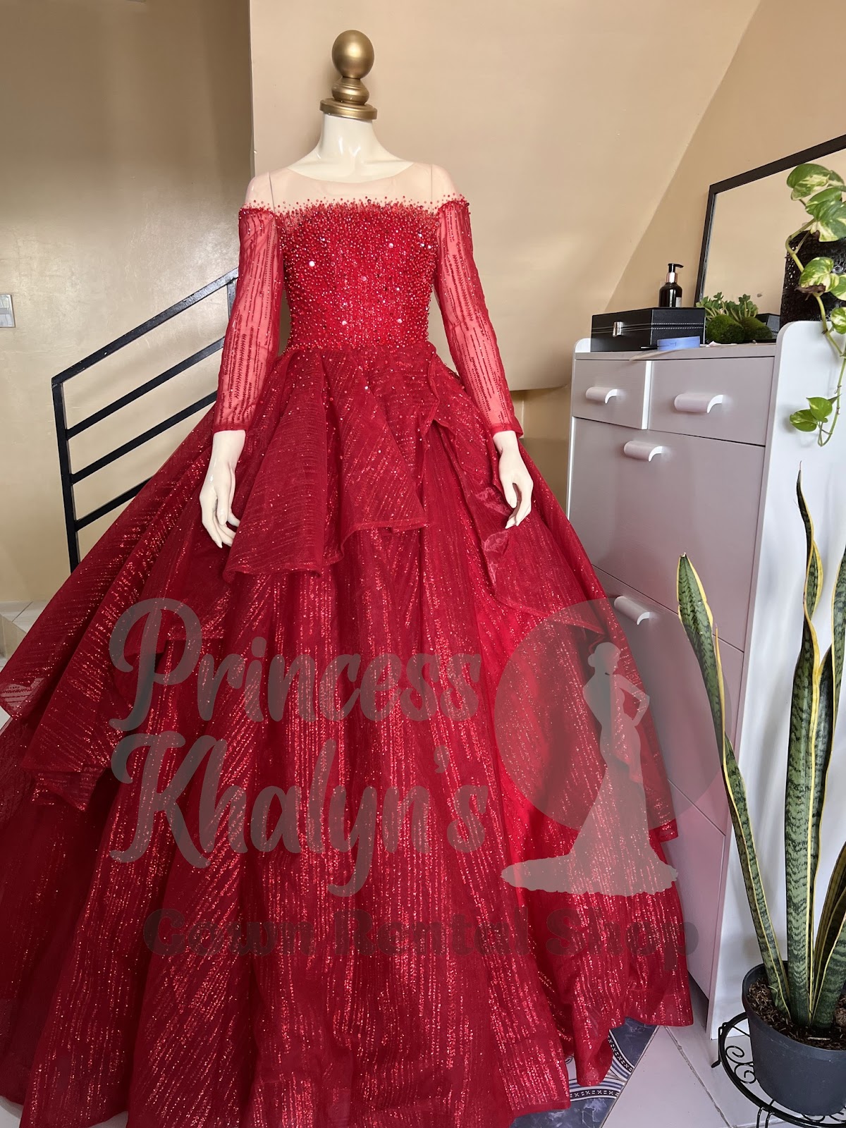 Red ball gown with illusion neckline, long beaded sleeves, and layered shimmering skirt