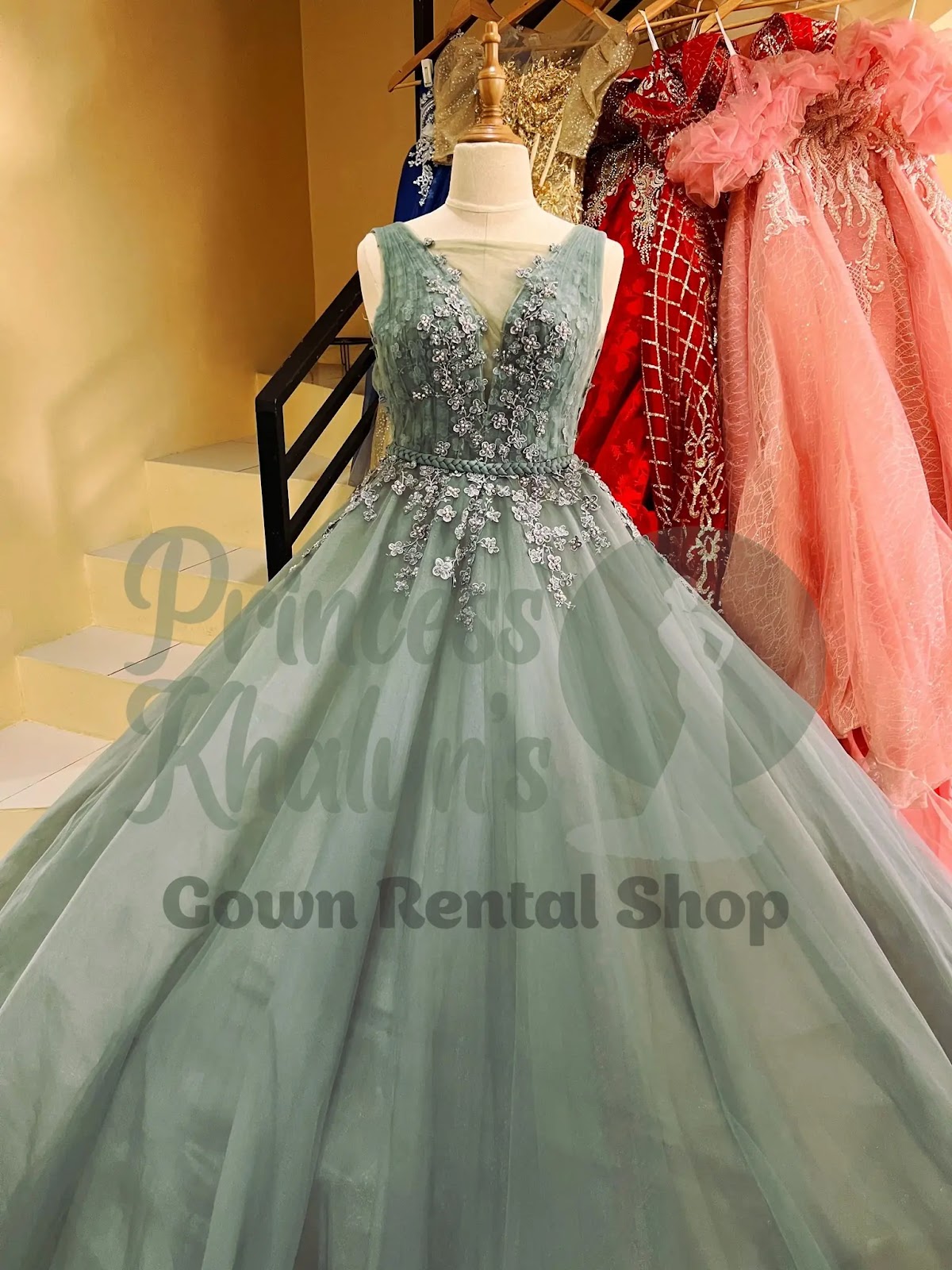 Sage green ball gown with sleeveless illusion neckline and delicate silver floral appliqué on the bodice and waist