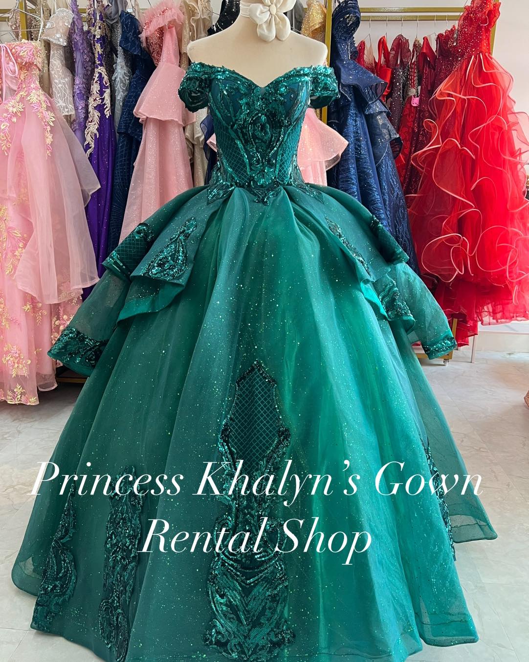 A stunning emerald green off-shoulder ball gown with intricate sequin embroidery and a voluminous layered skirt. The gown features a fitted bodice with ornate detailing, creating an elegant and regal appearance.
