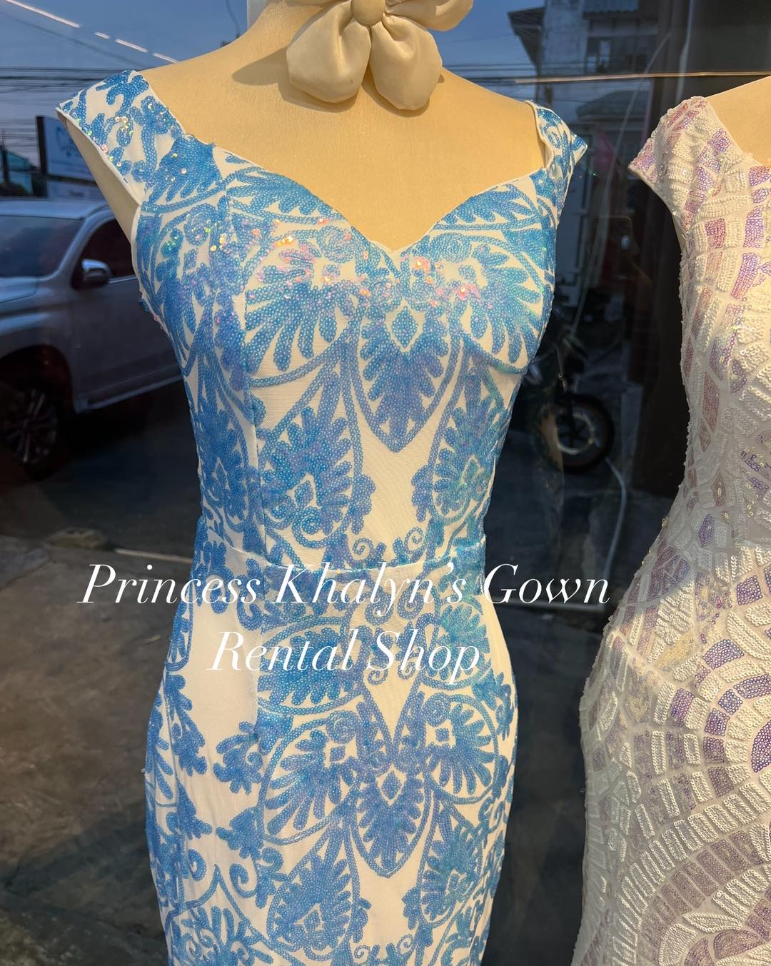 A fitted blue gown with intricate lace patterns over a white base, featuring a sweetheart neckline and cap sleeves, perfect for formal events.