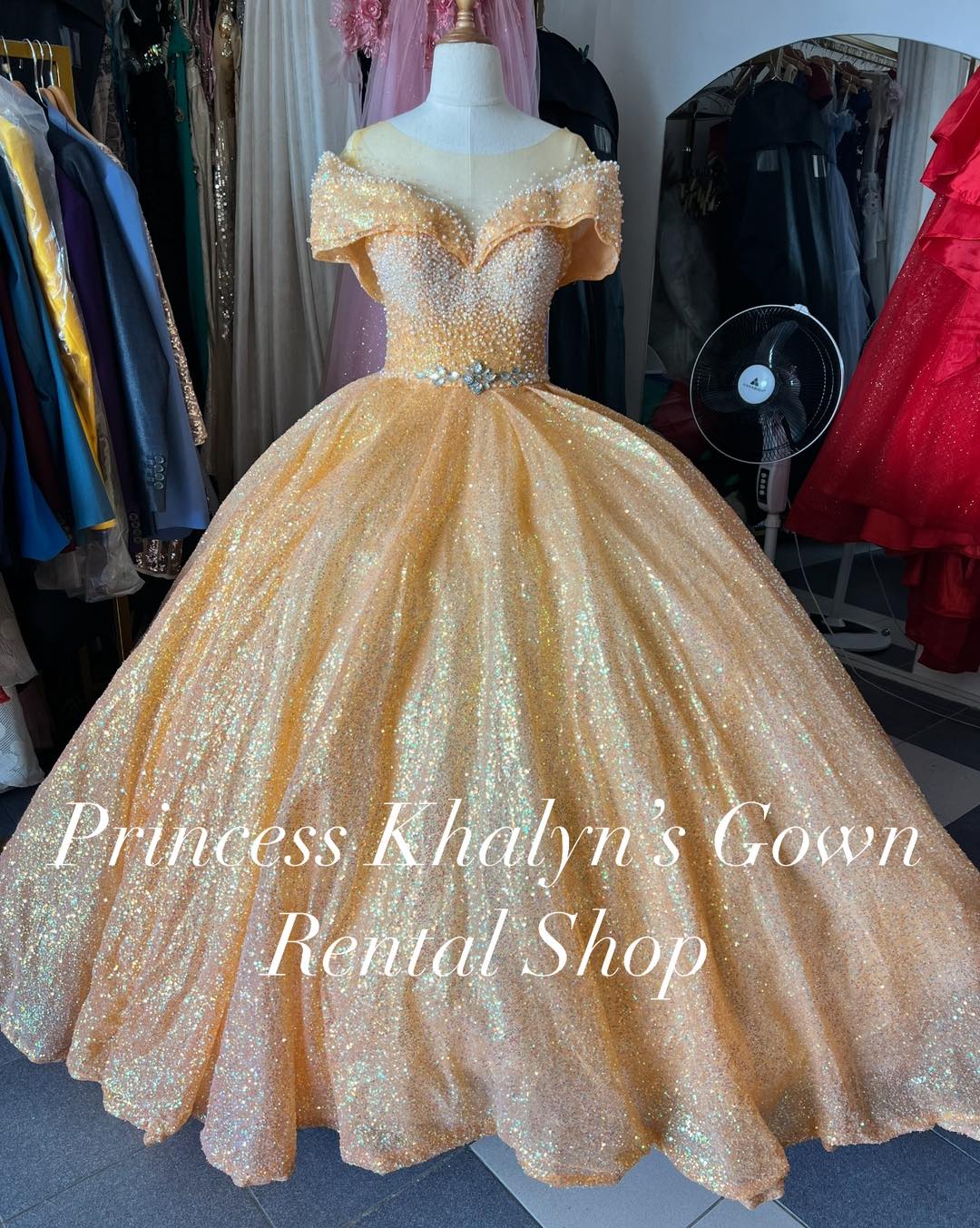 A dazzling gold off-shoulder ball gown with a shimmering bodice adorned with pearl-like embellishments and a voluminous glittering skirt, perfect for formal events.