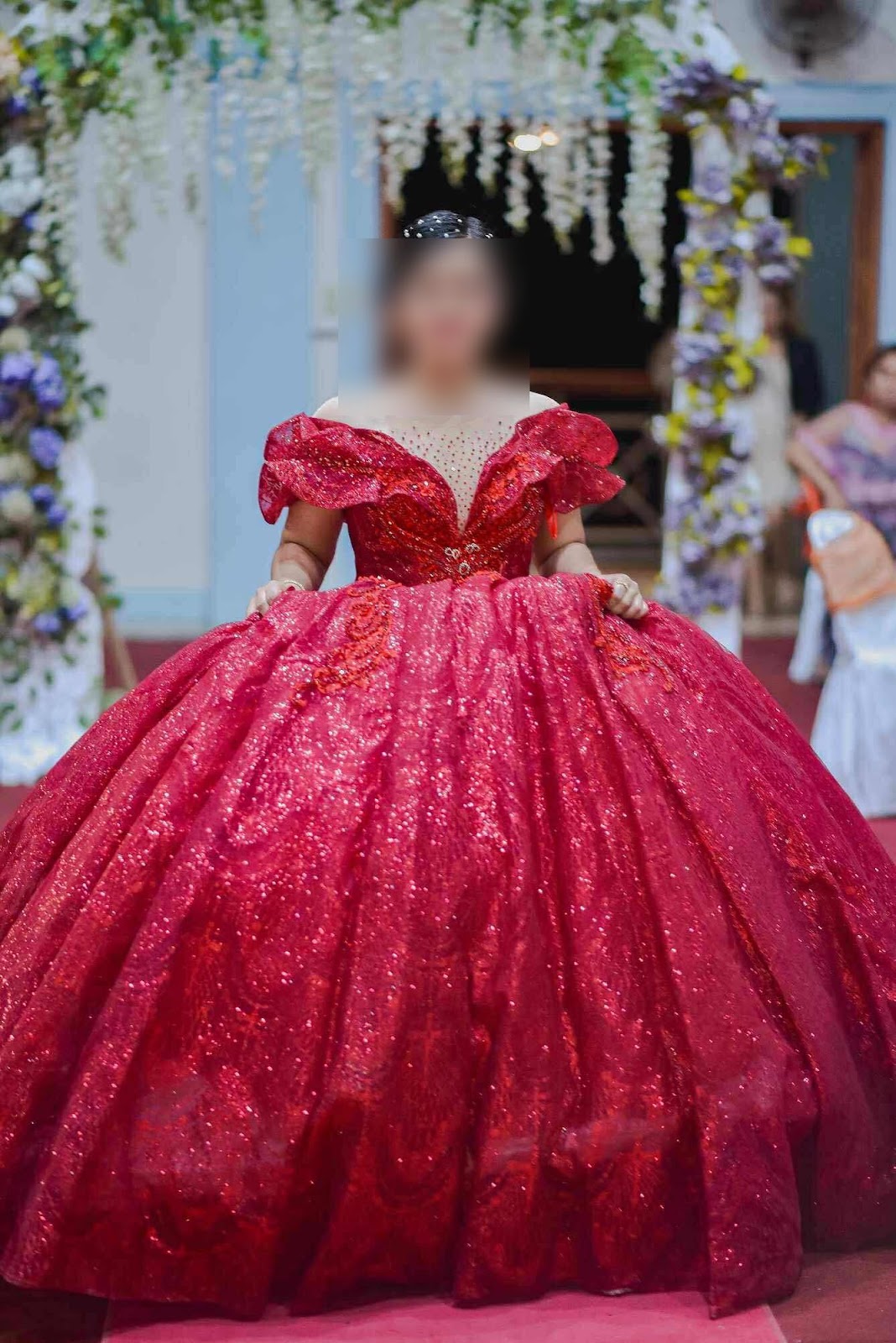 A stunning crimson ball gown adorned with sparkling sequins, featuring an off-shoulder neckline and a voluminous skirt that adds an enchanting flair.
