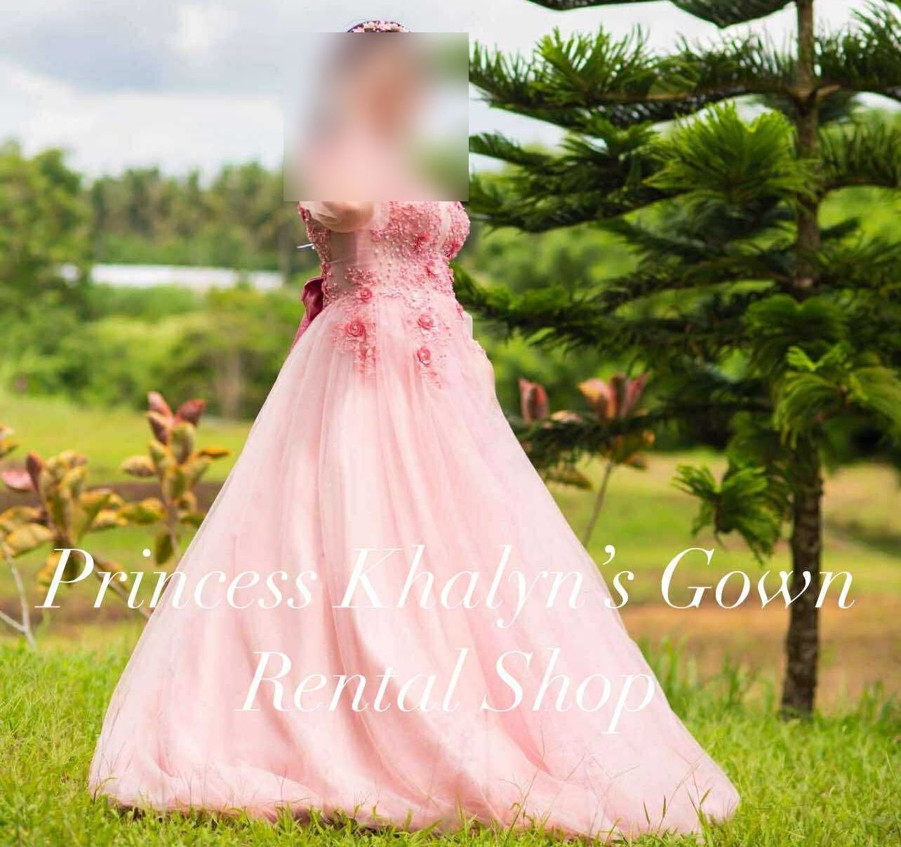 A stunning pink gown adorned with delicate floral embellishments, featuring a flowing skirt that adds an air of elegance and charm.