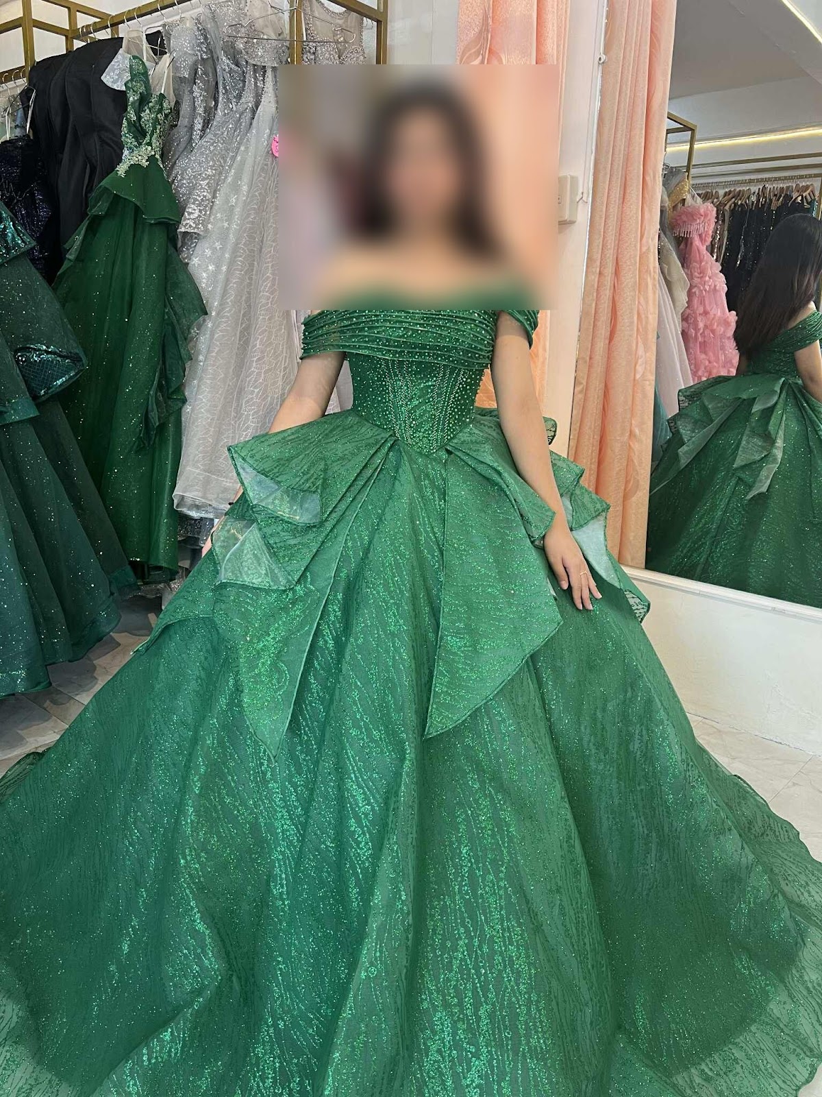 A stunning emerald green gown featuring an off-the-shoulder neckline and layered skirt, adorned with intricate detailing for a captivating look.