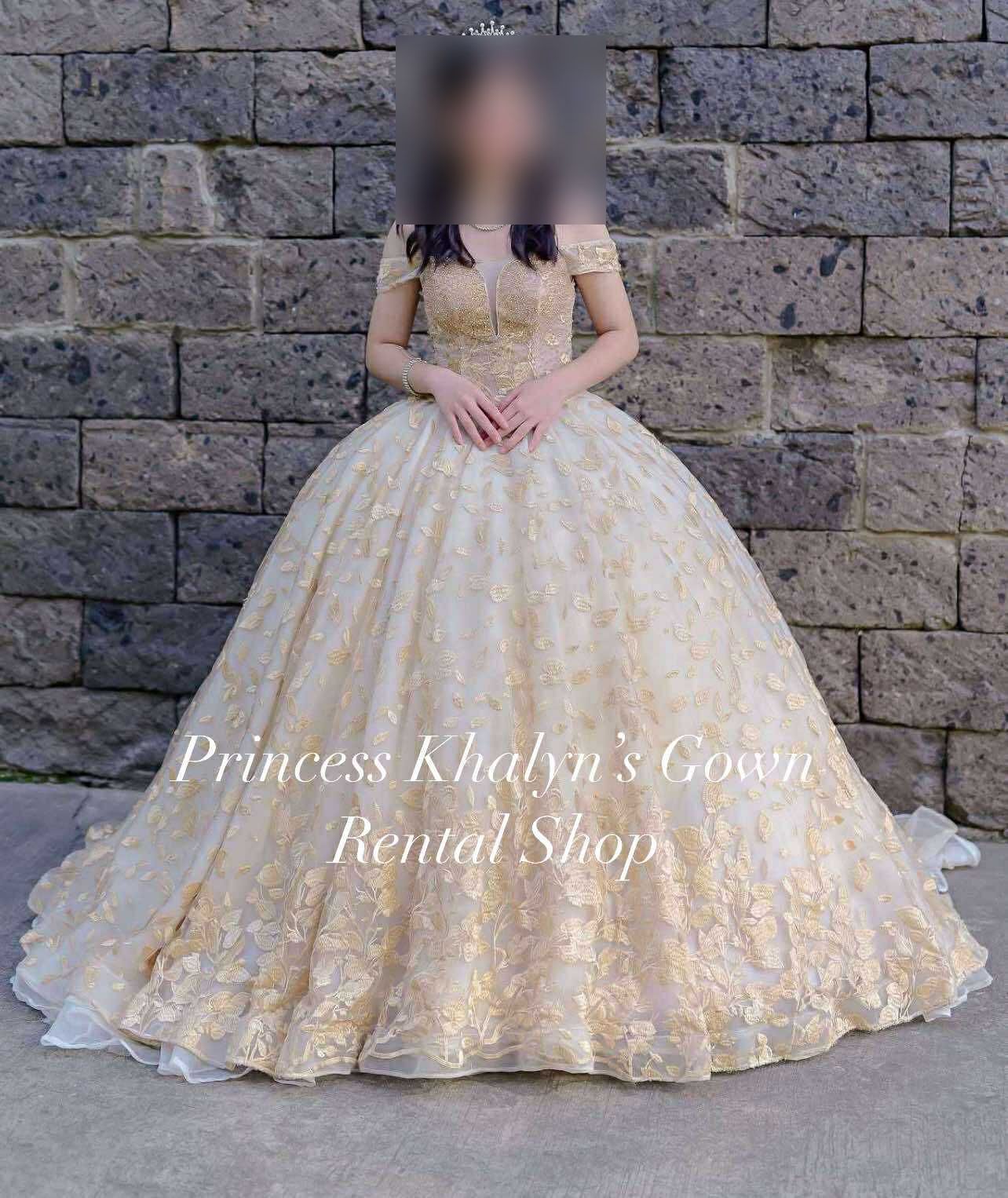 A stunning gold gown adorned with delicate floral embroidery, featuring a fitted bodice and a voluminous skirt, perfect for making a statement at any formal event.