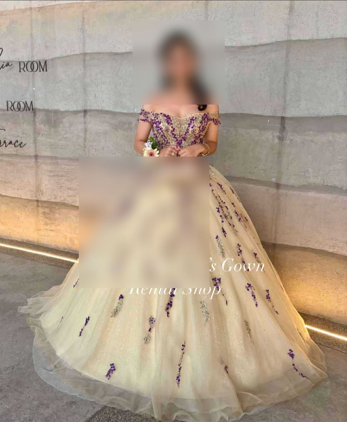 An exquisite gold ball gown featuring elegant off-the-shoulder sleeves adorned with delicate lavender floral embroidery, complemented by a voluminous skirt that adds a touch of fairy-tale charm.